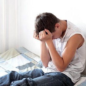 Picture of teenage boy on his bed upset